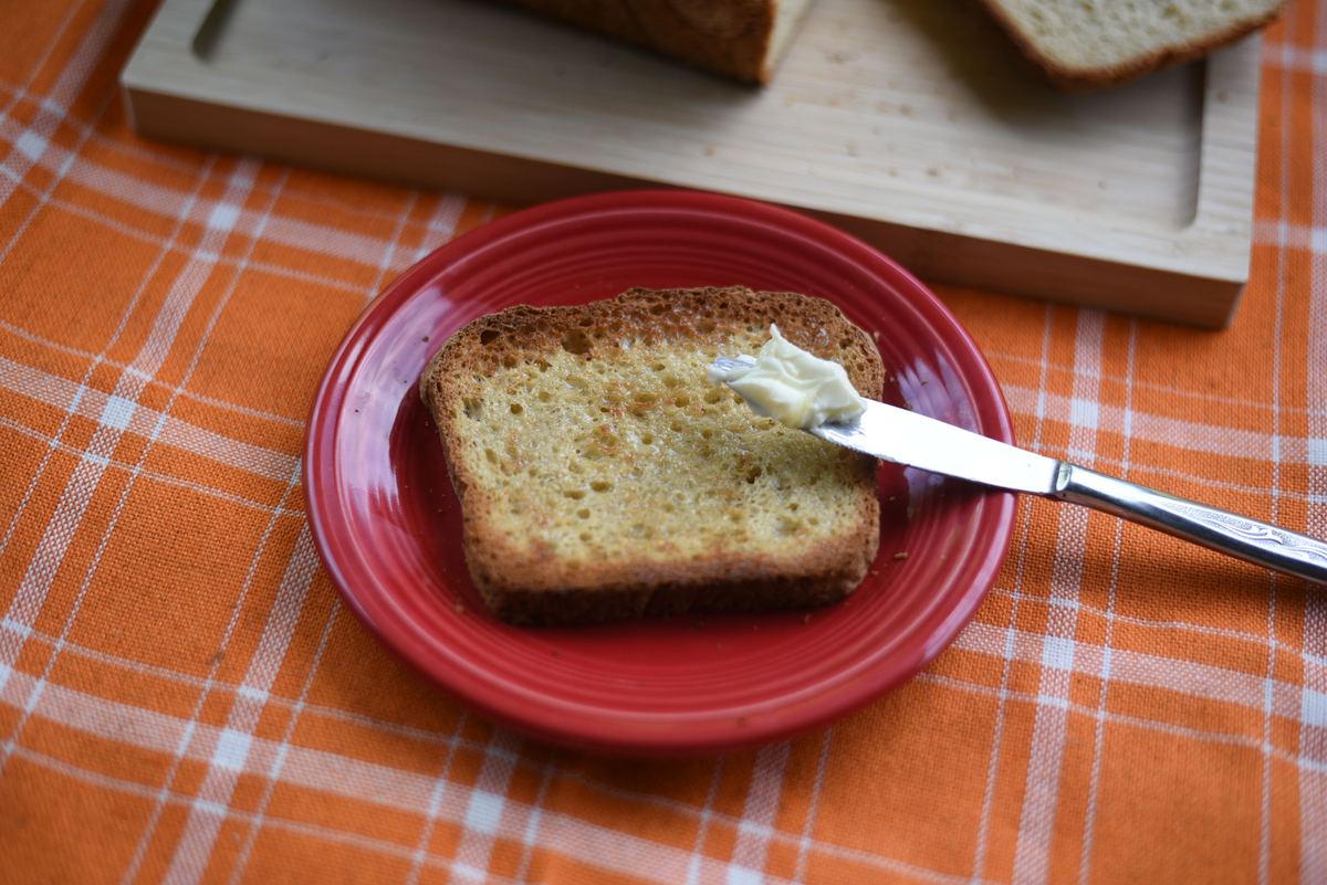 A slice of toasted gluten-free bread with butter on a red plate