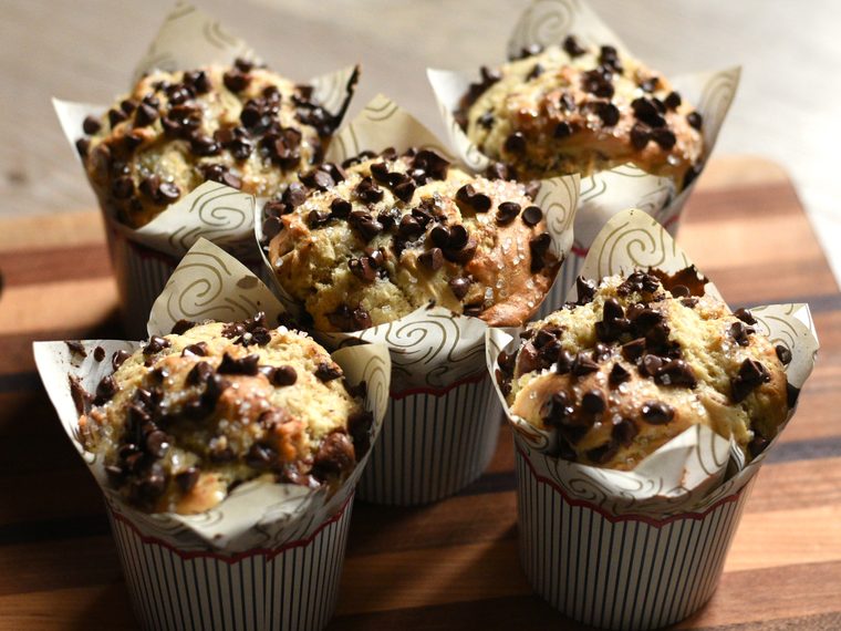 Chocolate chip muffins with sugar-crusted tops on a wooden board