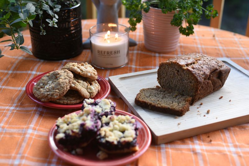 Cookies, blueberry crumb bars and a sliced loaf laid out on a table
