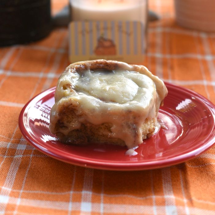 A frosted cinnamon roll on a red plate